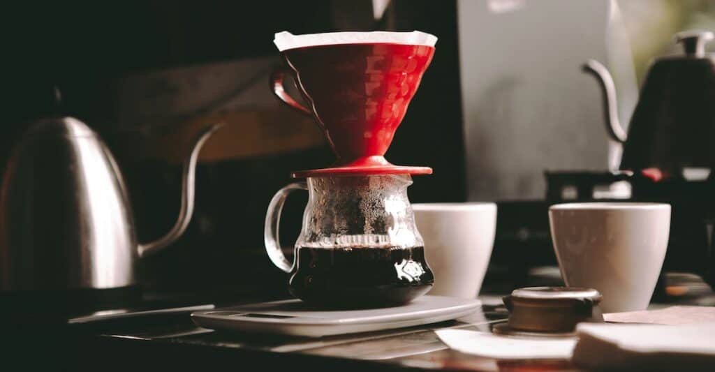 Coffee gifts including grinder, pour over brewer, and fresh coffee beans on wooden table